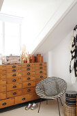 Black-and-white patterned easy chair next to old chest of drawers