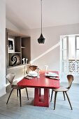 Red oak table and designer chairs below pendant lamp in dining room