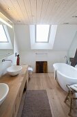 Free-standing bathtub and custom washstand in modern designer bathroom in attic