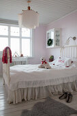 Metal bed with loose cover and ruffles in child's bedroom with pale pink walls