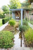 Straight stream leading to wooden house between flowerbeds
