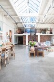 Open-plan eclectic interior in converted building with gallery and continuous ridge skylight