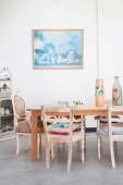 Vintage armchairs and dining table on concrete floor in front of framed picture of cherubs