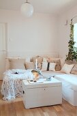 Scatter cushions on corner sofa and candles arranged on white trunk in Scandinavian living room
