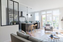Glass partition, black fitted kitchen and island counter in open-plan living space