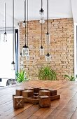 Dining table made from reclaimed materials below pendant lamps made from recycled glass