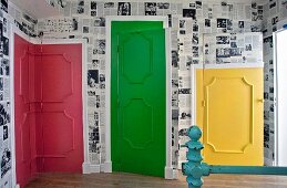 Colourful panelled doors on landing with black and white newspaper-style wallpaper
