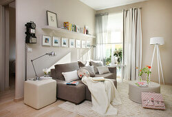 Sofa, standard lamp and floating shelf in cosy, beige living room