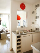 Kitchen cabinets with integrated wine rack and sink below serving hatch in corner of kitchen