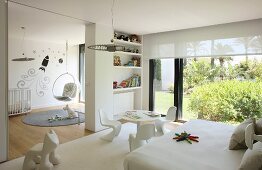 White, modern nursery with glass wall leading to garden