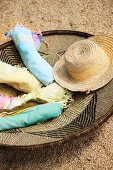 Rolled towels and straw hat in woven basket with ethnic pattern