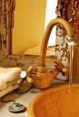 Water running from vintage sink tap in front of shabby-chic framed mirror