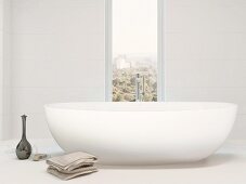 White free-standing bathtub next to vertical window with view