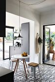 Schwarze Einbauküche mit floralem Bodenfliesen-Muster und geöffneten Terrassentüren