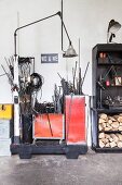 Metal rods in red containers and logs on black shelves in lamp manufactory