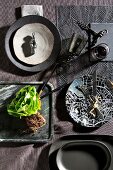 Crockery in earthy tones and black and lettuce on stone tray