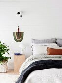 Bright bedroom with white painted wooden cladding and fans as wall decoration