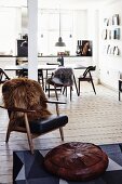 Brown fur blanket on retro armchair and pouffe in open-plan living room