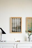 Two abstract artworks in wooden frames above sideboard