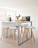 Bar stools around island counter in white modern kitchen