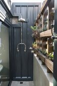 Vintage-style outdoor shower next to planted rustic wooden screen