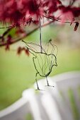 Delicate hand-made wire bird hung from branch