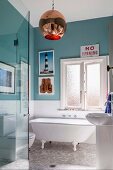 Bathroom with nostalgic freestanding bathtub, turquoise green wall paint and retro ball lamp; eclectic flair