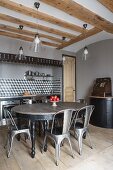 Oval table and classic chairs in front of kitchen counter built into large niche in wall