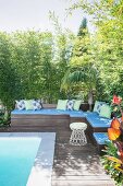 Outdoor wooden lounge area by the pool with blue upholstery and decorative pillows