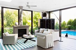 Summery living room with window front to the garden with pool