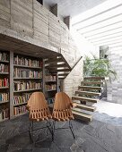 Designer chairs in front of bookcase in concrete house