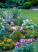 Woman sculpture on stone with Sempervivum (houseleek) in flowerbed