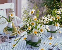 Table decoration with daisies in small bottles