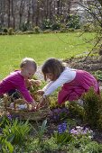 Kinder mit Osternest im Garten
