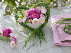 Bouquet of rose and daisies in a grass heart