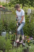 Young woman planting summer flower bed