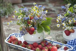 Kleine Sträuße aus blühenden Kräutern und frischgepflückte Erdbeeren