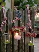 Preserving jars hung on fence as lanterns, small wreaths