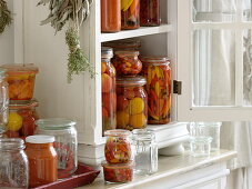 Small cupboard with cooked tomatoes in vinegar, hot peppers and tomato sugo