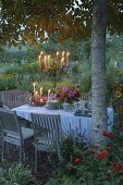 Gedeckter Tisch im Blumengarten unter Walnussbaum
