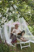 Lounger with mosquito net on the meadow under the apple tree