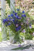Blue bouquet of Aquilegia and grasses in glass bowl