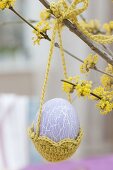 Easter egg in crochet basket on Cornus mas branch