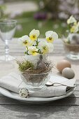 Easter table decoration with horned violets on the terrace