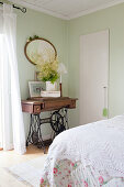 Alter Nähmaschinentisch im nostalgischen Schlafzimmer mit blassgrünen Wanden