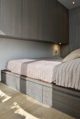 Einbaumöbel und Bett mit Bettschubladen in reduziertem Schlafzimmer