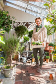 Various potted plants and woman in bright greenhouse