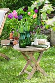 Tulips in green glass vases on garden table