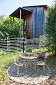 Vintage table and chairs on terrace in garden outside house with wooden façade