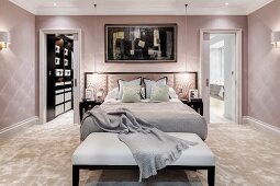 Glamorous bedroom in pastel shades with bench at foot of bed
